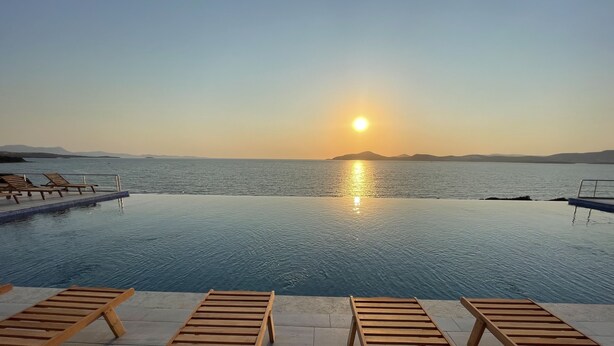 A poolside view with lounge chairs and a sunset over the water. - Ni Marin Hotel (Milas)