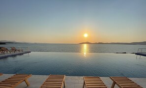 A poolside view with lounge chairs and a sunset over the water. - Ni Marin Hotel (Milas)