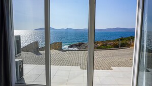 A view from a window overlooking a paved area with a body of water and distant mountains. - Ni Marin Hotel (Milas)