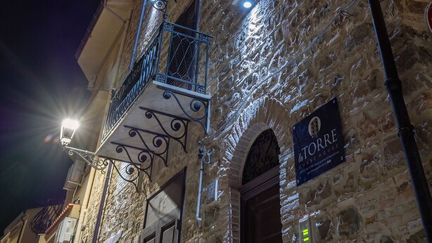 Een stenen gebouw met een bordje voor 'La Torre Guest House' in de nacht.