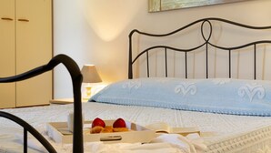 A neatly made bed with a blue pillow, a bedside table with a lamp, and a box of food items.