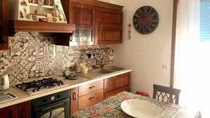 Una cocina con baldosas estampadas, armarios de madera, una estufa a gas y un reloj de pared.