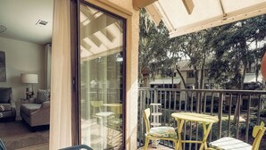 A balcony with a sofa, chairs, and a table. - Home away from Home. Fresh, Bright Condo just steps away from the beach (Hilton Head Island)