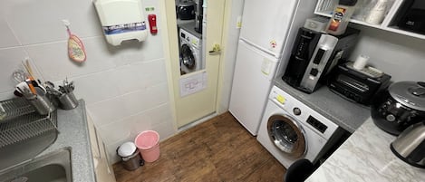 Une cuisine compacte équipée d’un lave-linge, d’un four à micro-ondes et d’une machine à café.