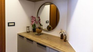 A bathroom with a wooden vanity, a round mirror, a globe, and a small potted plant. - Apartment Blaue Adria (Split)