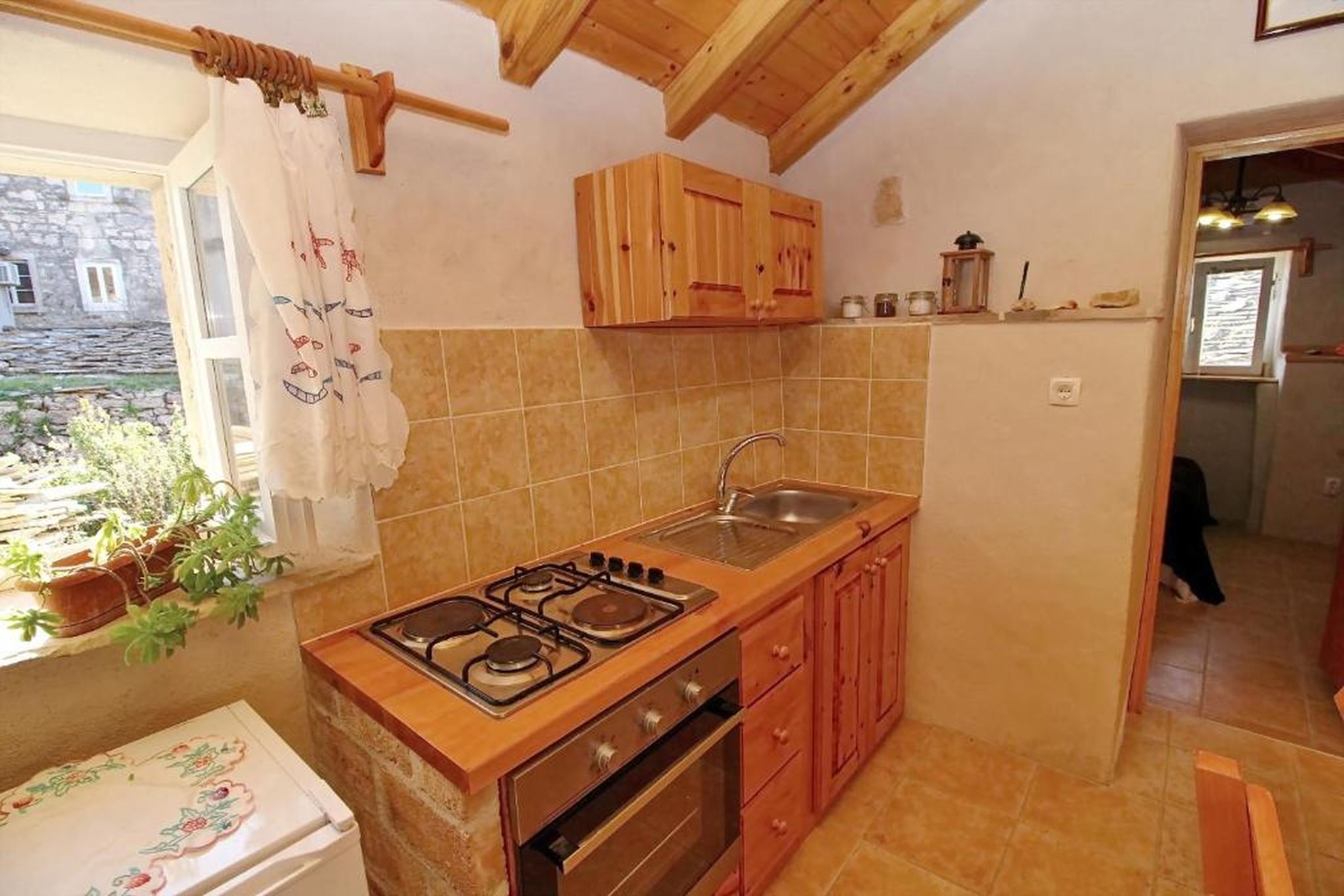 A compact kitchen with wooden cabinets, a gas stove, and a sink.