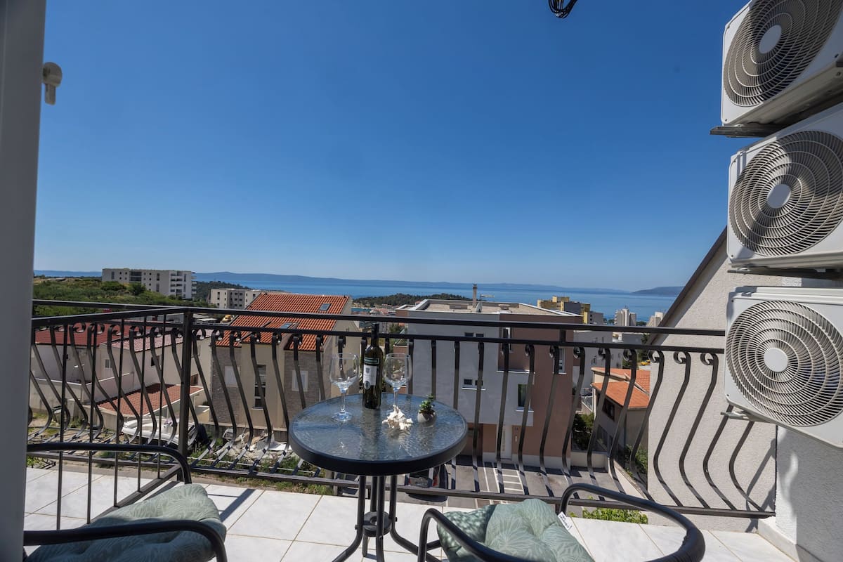 Un balcón con mesa, sillas y vista al mar.
