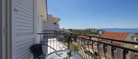 A balcony with a table, two chairs, a bottle of wine, and a decorative item.