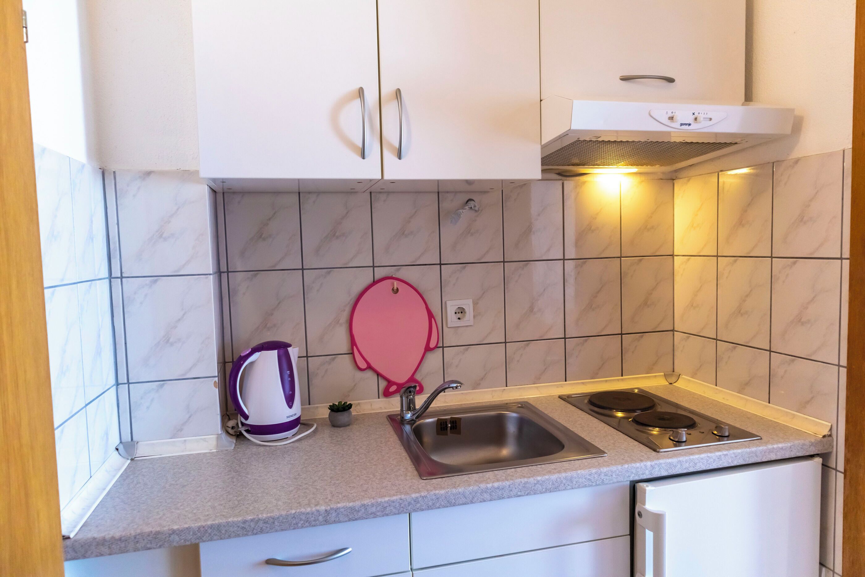 A kitchen with white cabinets, a stainless steel sink, a gas stove, and a microwave.