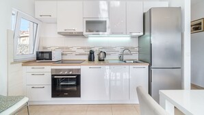 A modern kitchen with white cabinets, a stainless steel refrigerator, a microwave, an oven, and a sink. - Apartment Magical View (Milna)