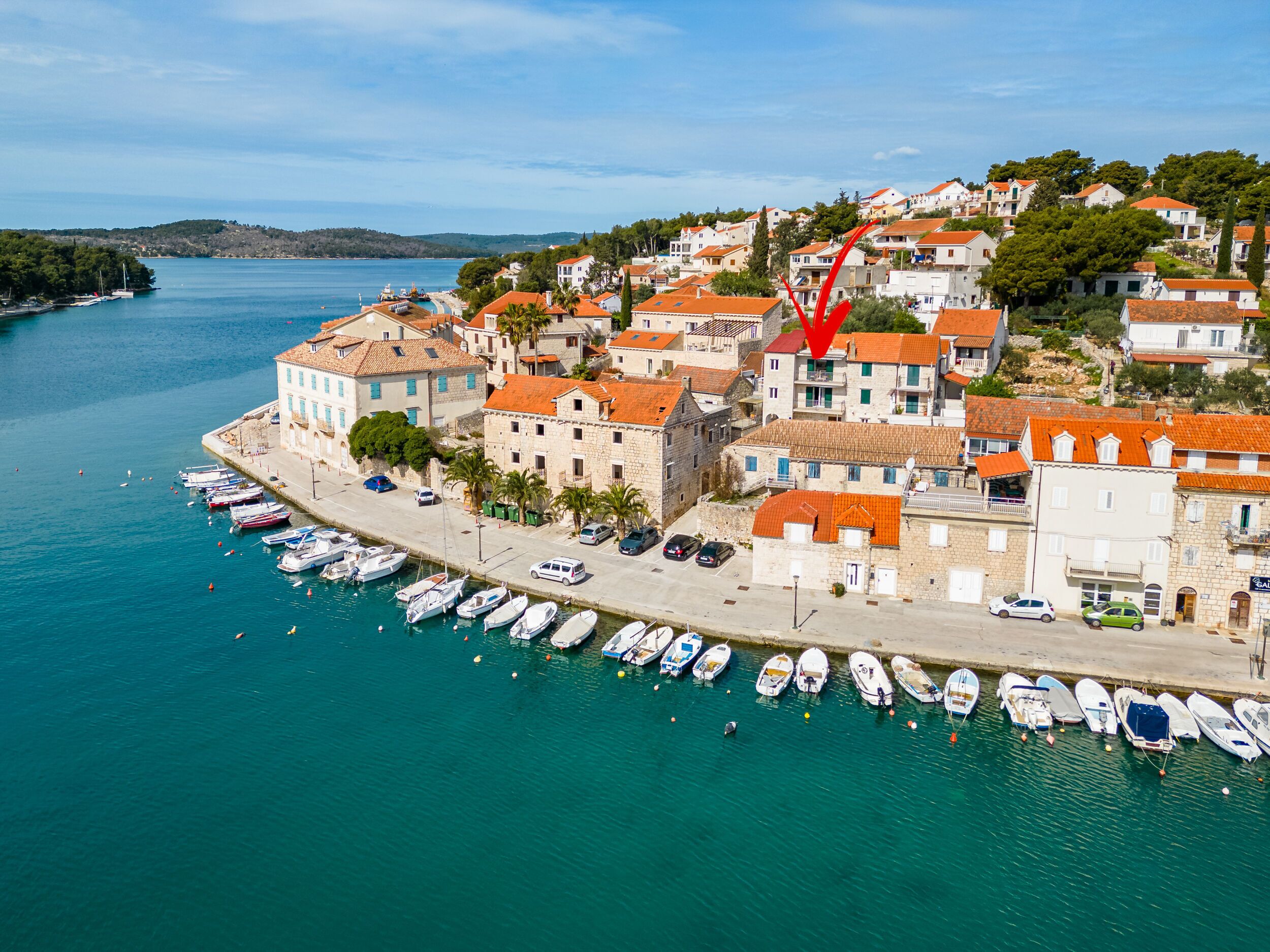 Une ville côtière dotée de bâtiments historiques, d’un port de plaisance avec des bateaux et offrant une vue dégagée sur la mer.