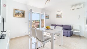 A modern living room with a dining area, a sofa, and a balcony with a city view. - Apartment Magical View (Milna)