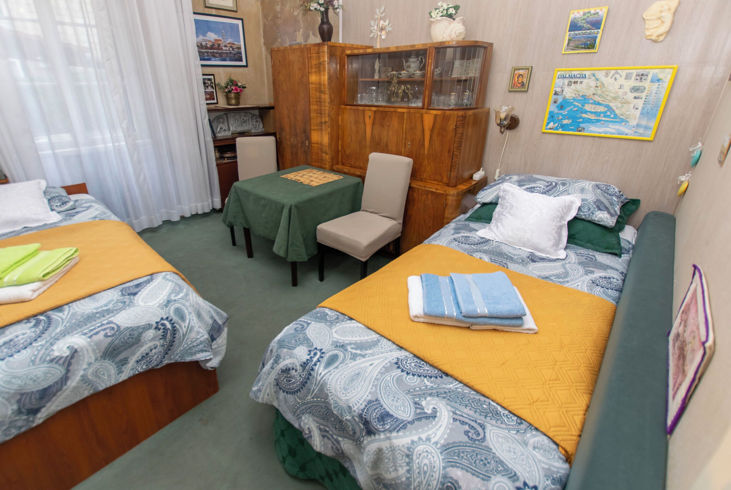 A hotel room with two beds, a wooden cabinet, a small table, and a chair.