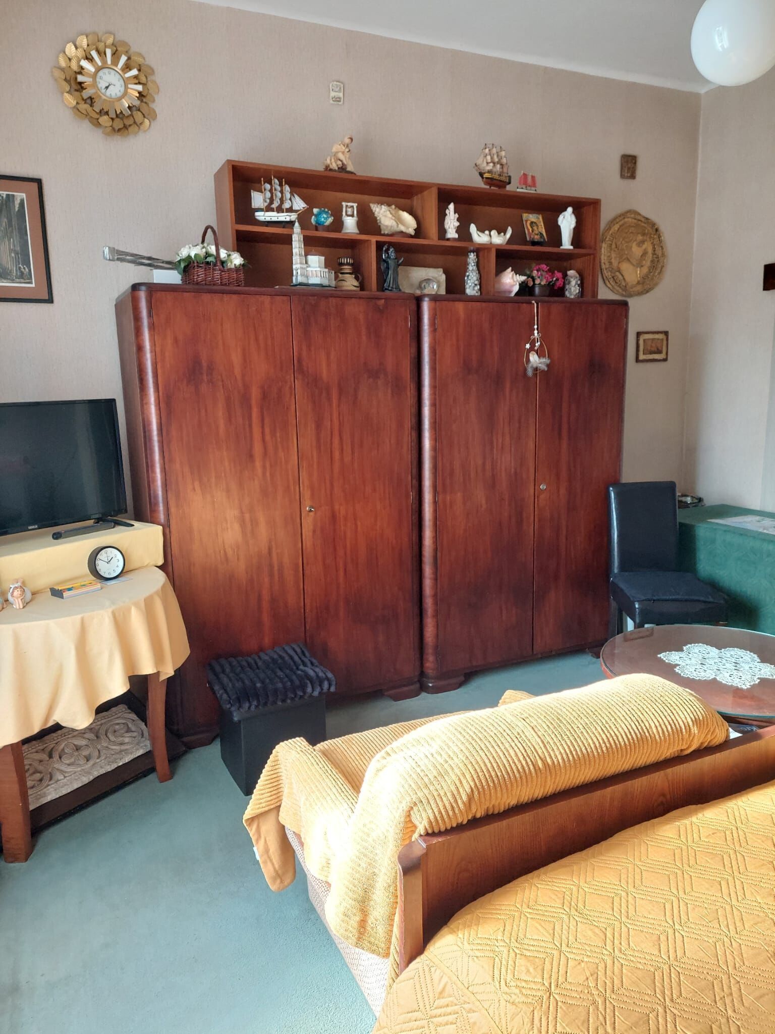 A living room with a wooden wardrobe, a television, a small table, and a sofa.