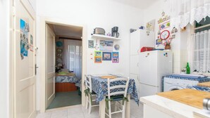 A compact kitchen with a dining area, a washing machine, and a small table with chairs. - Apartment Zeljana (Split)