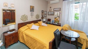 A hotel room with a large bed, a small table, a chair, a desk, and a mirror. - Apartment Zeljana (Split)