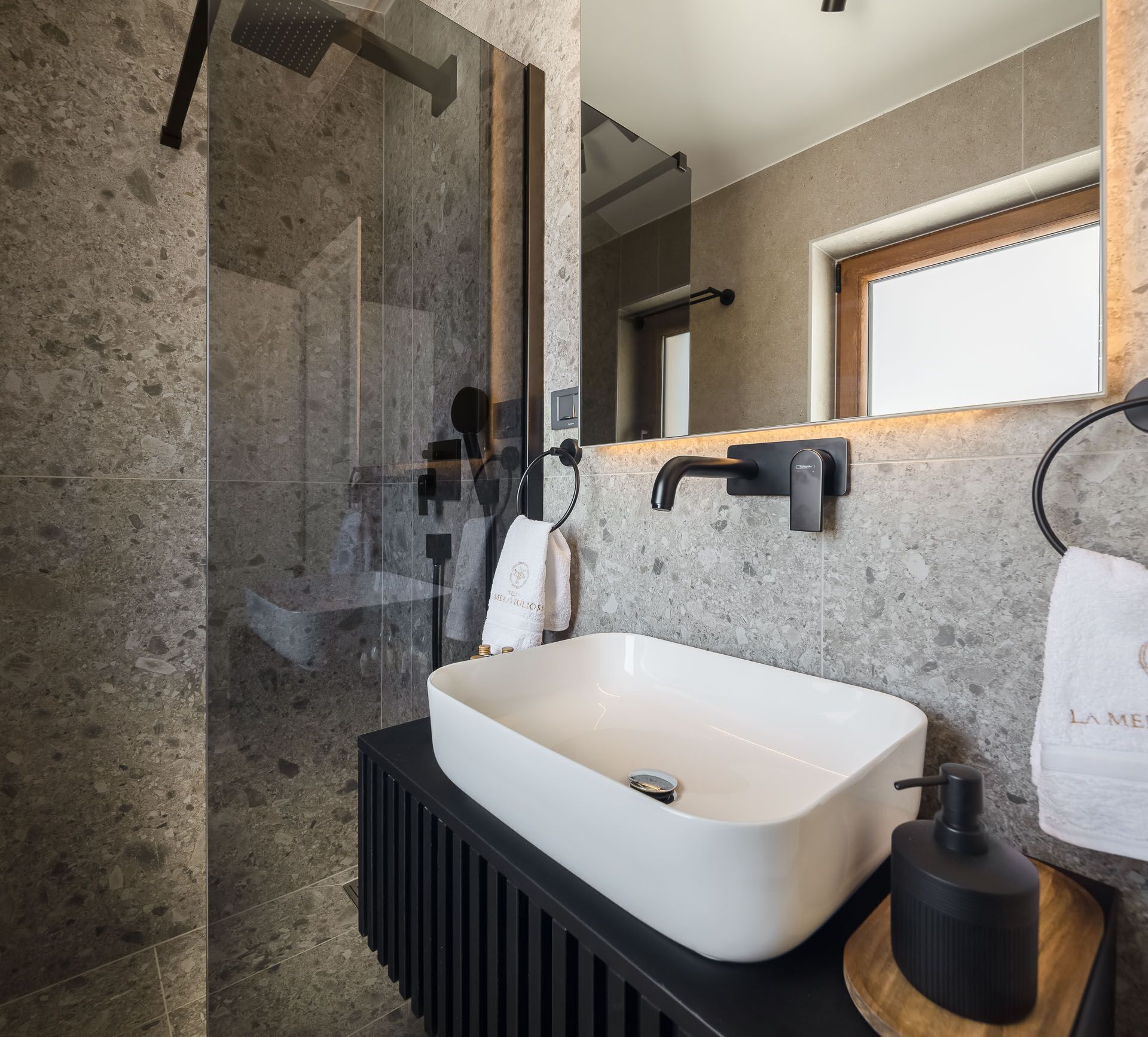 A modern bathroom with a rectangular sink, a glass shower enclosure, and a wooden vanity.