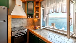 Una cocina con estufa, horno y vista al mar a través de una ventana.