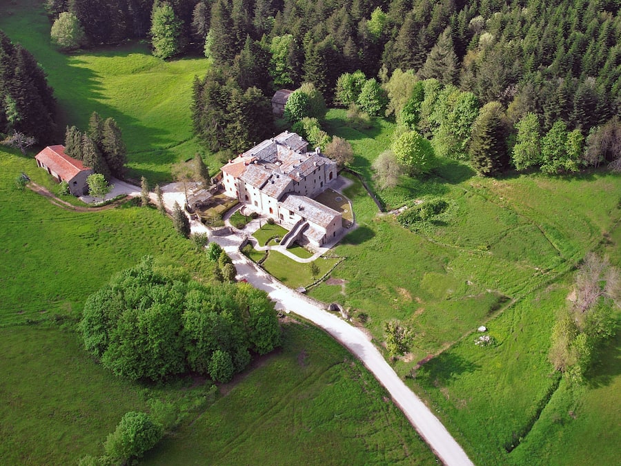 An aerial view of a large estate with multiple buildings, a central courtyard, and surrounding green fields.