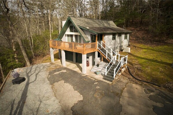 Situated in a wooded area, this cabin features a spacious deck with a railing and stairs leading to the entrance.
