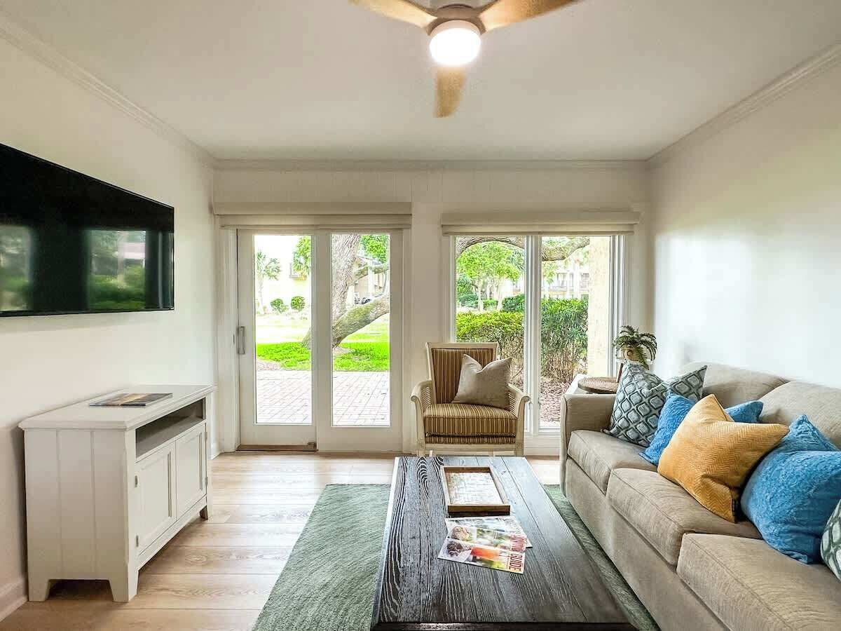 A living room with a sofa, coffee table, TV, and a sliding glass door leading to a garden.