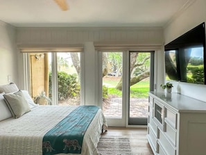 A bedroom with a bed, a television, a dresser, and a sliding glass door leading to a patio.