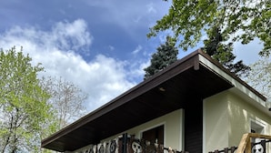 Een huis met een houten omheining, een veranda en een trap naar de ingang.