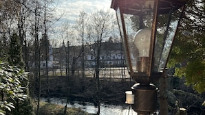 Een park met een vijver, bomen en een lantaarnpaal.