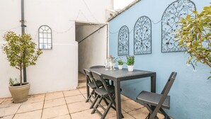 A patio with a table and chairs, potted plants, and decorative metal wall art. - Spinners House (Dartmouth)