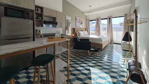 Ein modernes Hotelzimmer mit Küche, Essbereich, Bett und Balkon.