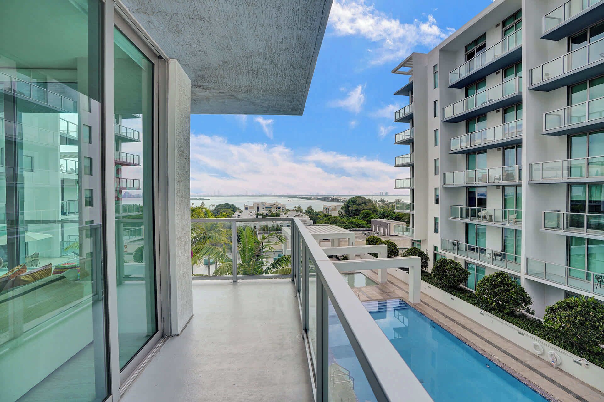 Un moderno edificio de apartamentos con piscina, amplias ventanas y vista al mar.