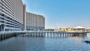 Ein Hotel am Wasser mit einer langen Anlegestelle, die sich ins Wasser erstreckt, mit mehreren Balkonen und einem großen, angrenzenden Gebäude.