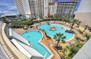 A resort with multiple swimming pools, palm trees, and a parking area. - Beach Lovers Retreat, Sleeps 7 (Panama City Beach)