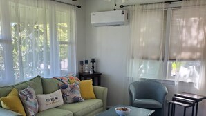 Una sala de estar con un sofá verde, una mesa de centro azul, un sillón gris y un ventilador de techo.
