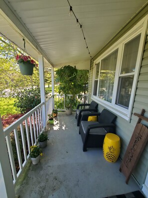 A covered porch with outdoor seating, potted plants, and a wooden sign. - Del Haven Delight (Middle Township)