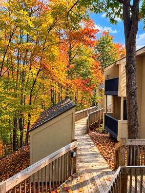 A wooden deck leading to a building with a beige exterior and a black-framed window. - Very Private Updated 2Br Condo on the Summit. Walking distance to all the fun. (Bellaire)
