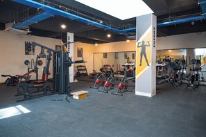 Uma academia com equipamentos de exercício, espelhos e um pilar grande com a palavra 'ENERGY' escrita.