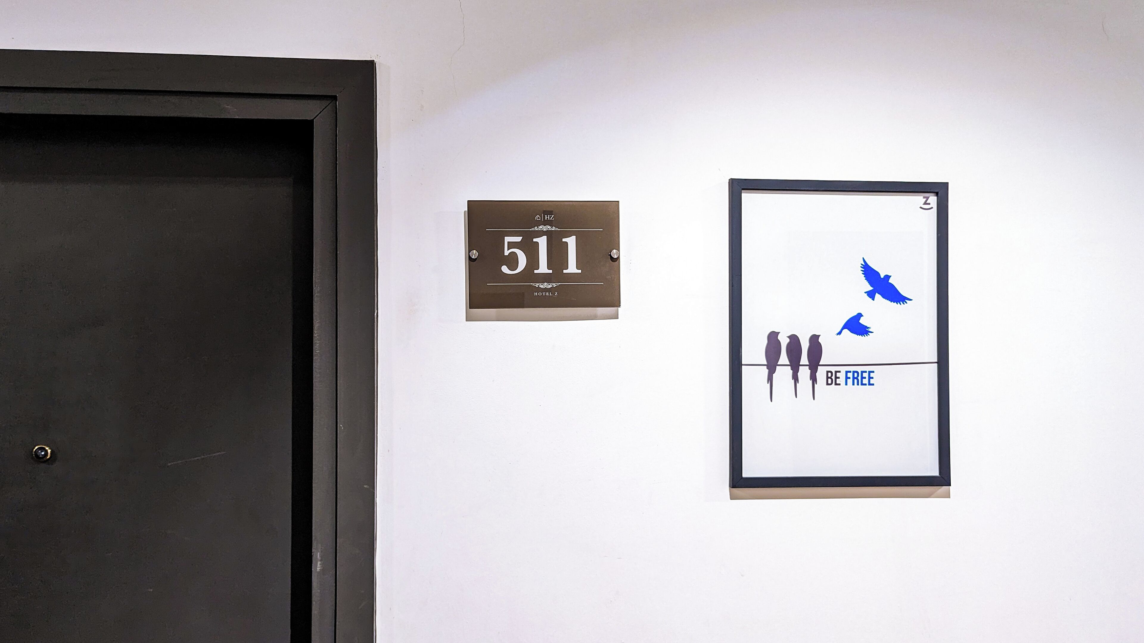 A door, a room number sign, and a framed artwork with birds and the text "BE FREE".