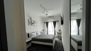 Une chambre d’hôtel moderne équipée d’un lit, d’une table de chevet, d’un miroir et d’un bureau avec une chaise.