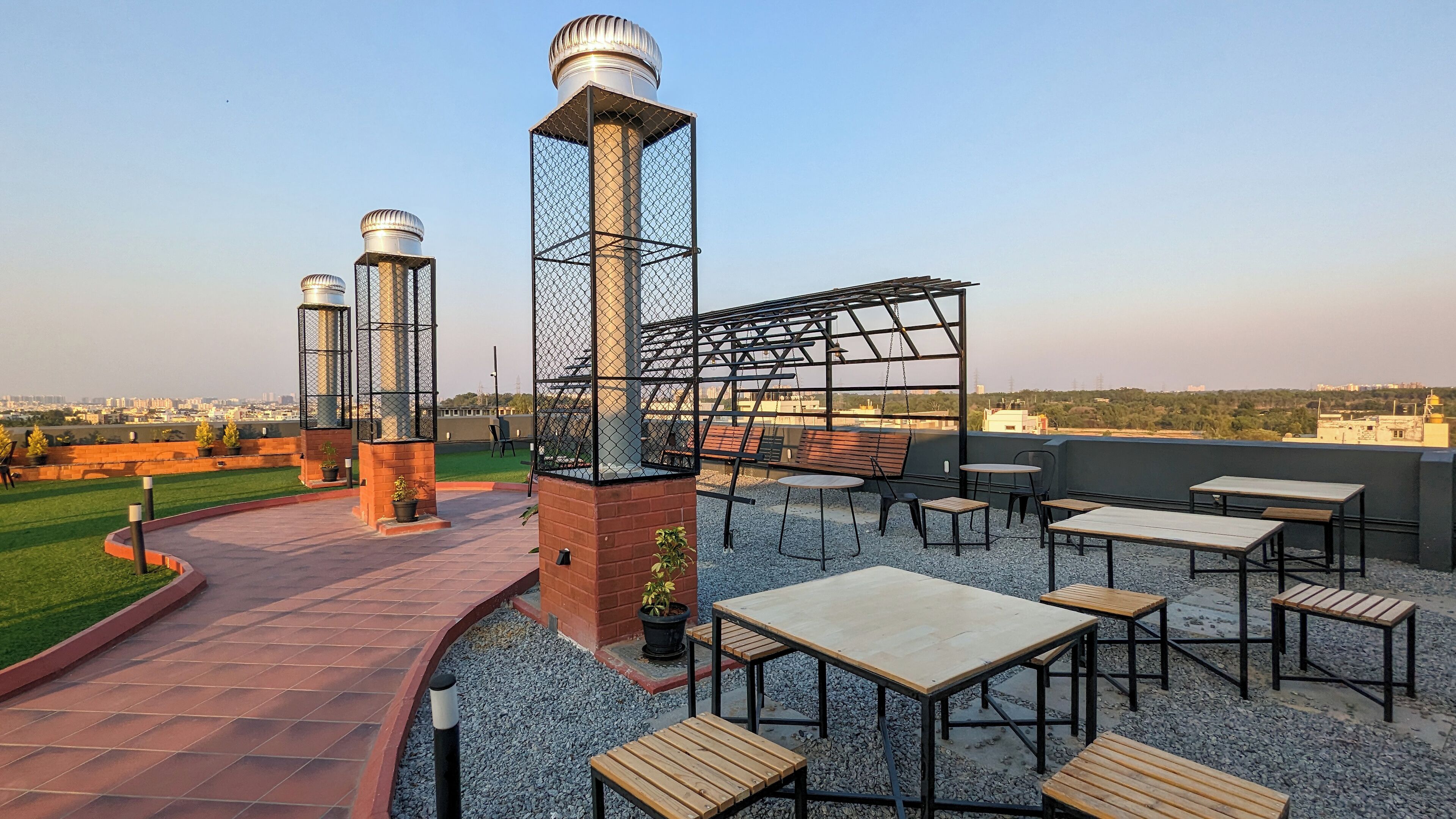A rooftop patio with outdoor seating, a pergola, and decorative metal structures.