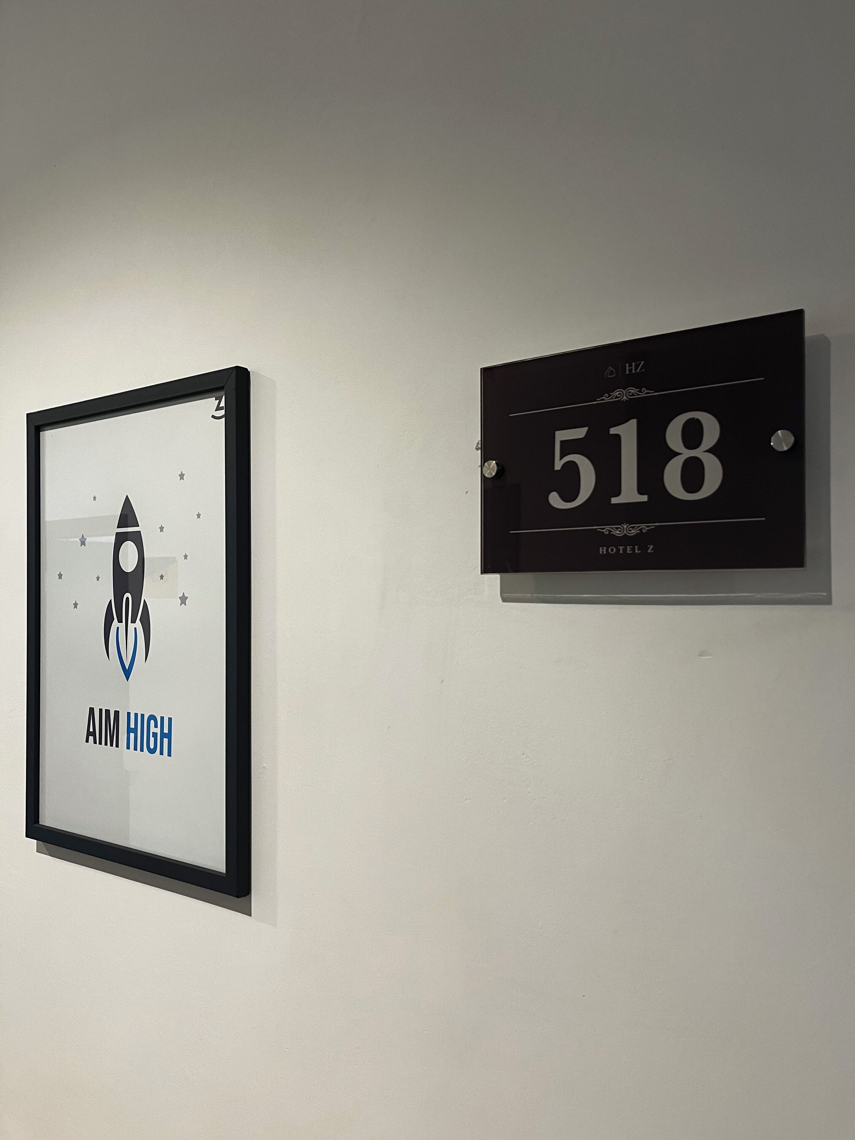 A framed picture with a rocket and the text "AIM HIGH" and a black sign with the number "518" and "HOTEL Z".