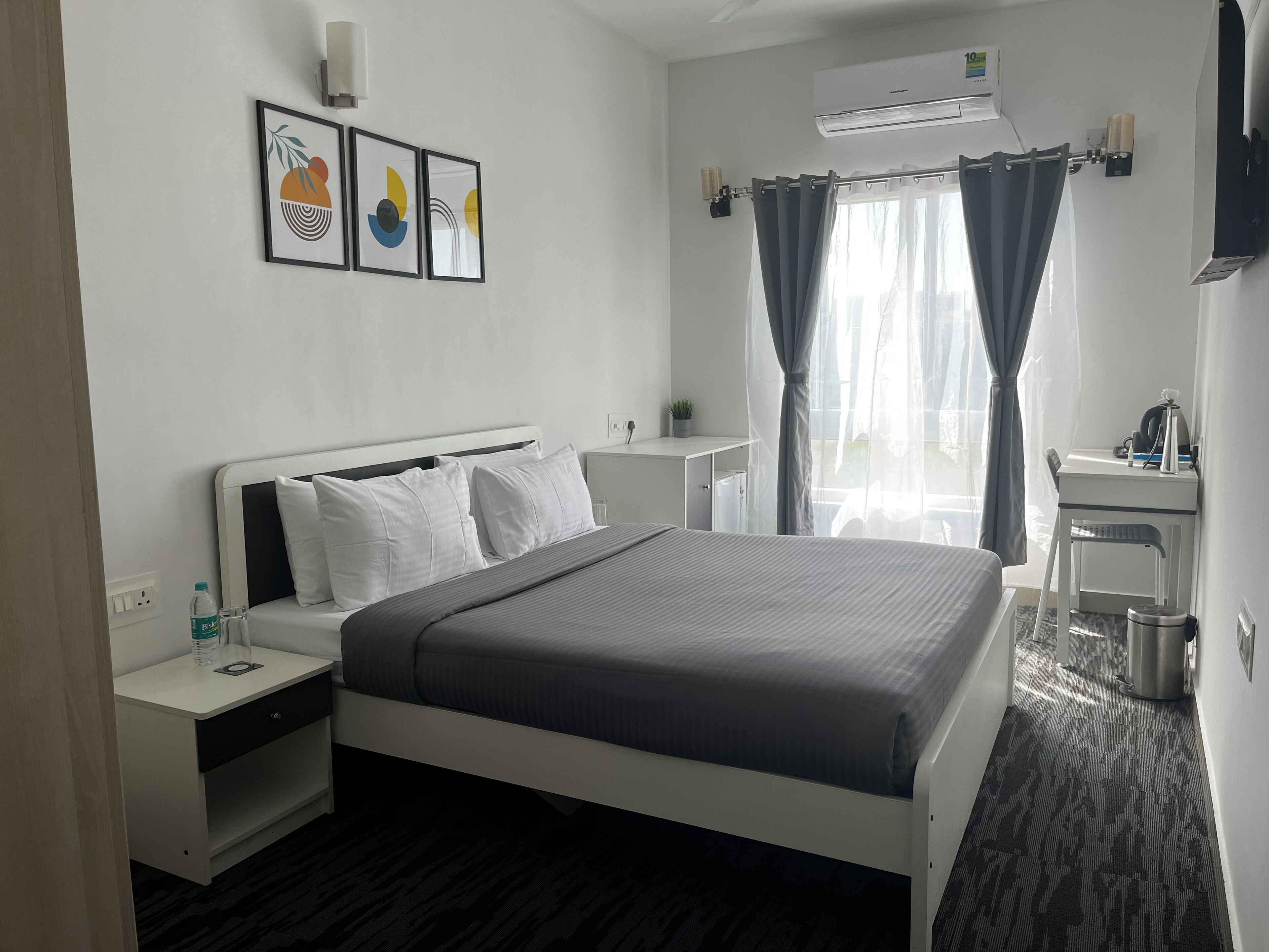 A hotel room with a bed, bedside tables, a desk, and a chair.