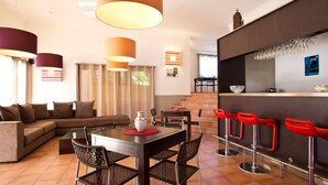 A modern living room with a sofa, dining table, and red bar stools. - Lagrange Vacances - Green Bastide (Roquebrune-sur-Argens)