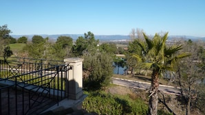 A view from a balcony with a railing, overlooking a landscape with trees, a body of water, and distant mountains. - Lagrange Vacances - Green Bastide (Roquebrune-sur-Argens)
