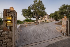 A stone pathway leading to a building with a large tree in the center. - Arca Villa - Enchanting Sunset! (Zakynthos)