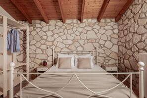 A bedroom with a stone wall, a wooden ceiling, a metal bed frame, and a small bedside table with a lamp. - Arca Villa - Enchanting Sunset! (Zakynthos)