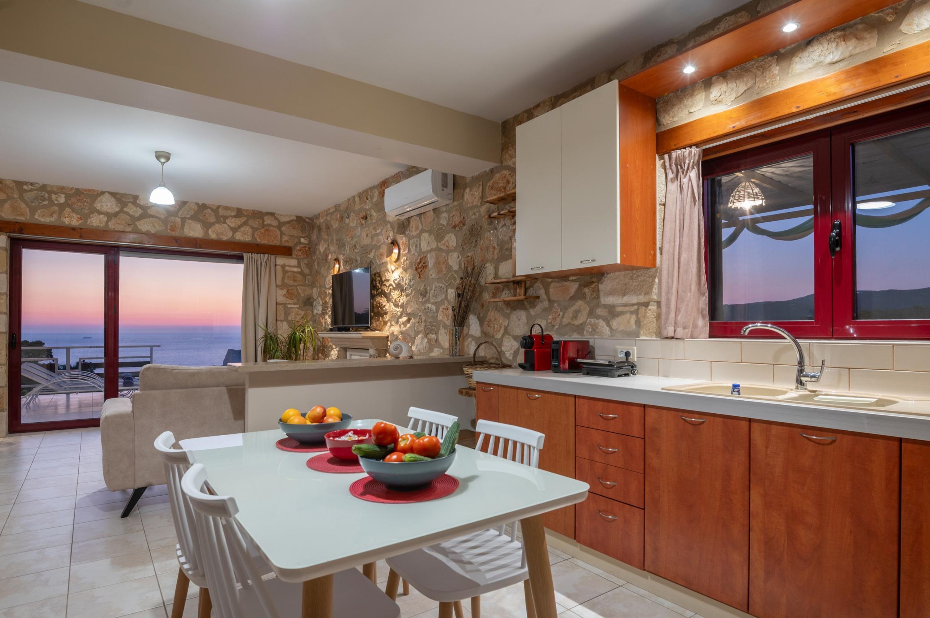 Una cocina moderna con paredes de piedra, armarios de madera y vista al mar.