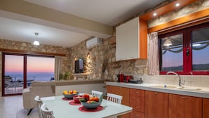 A modern kitchen with stone walls, wooden cabinets, and a view of the sea. - Arca Villa - Enchanting Sunset! (Zakynthos)