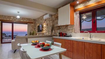Una cocina moderna con paredes de piedra, armarios de madera y vista al mar.