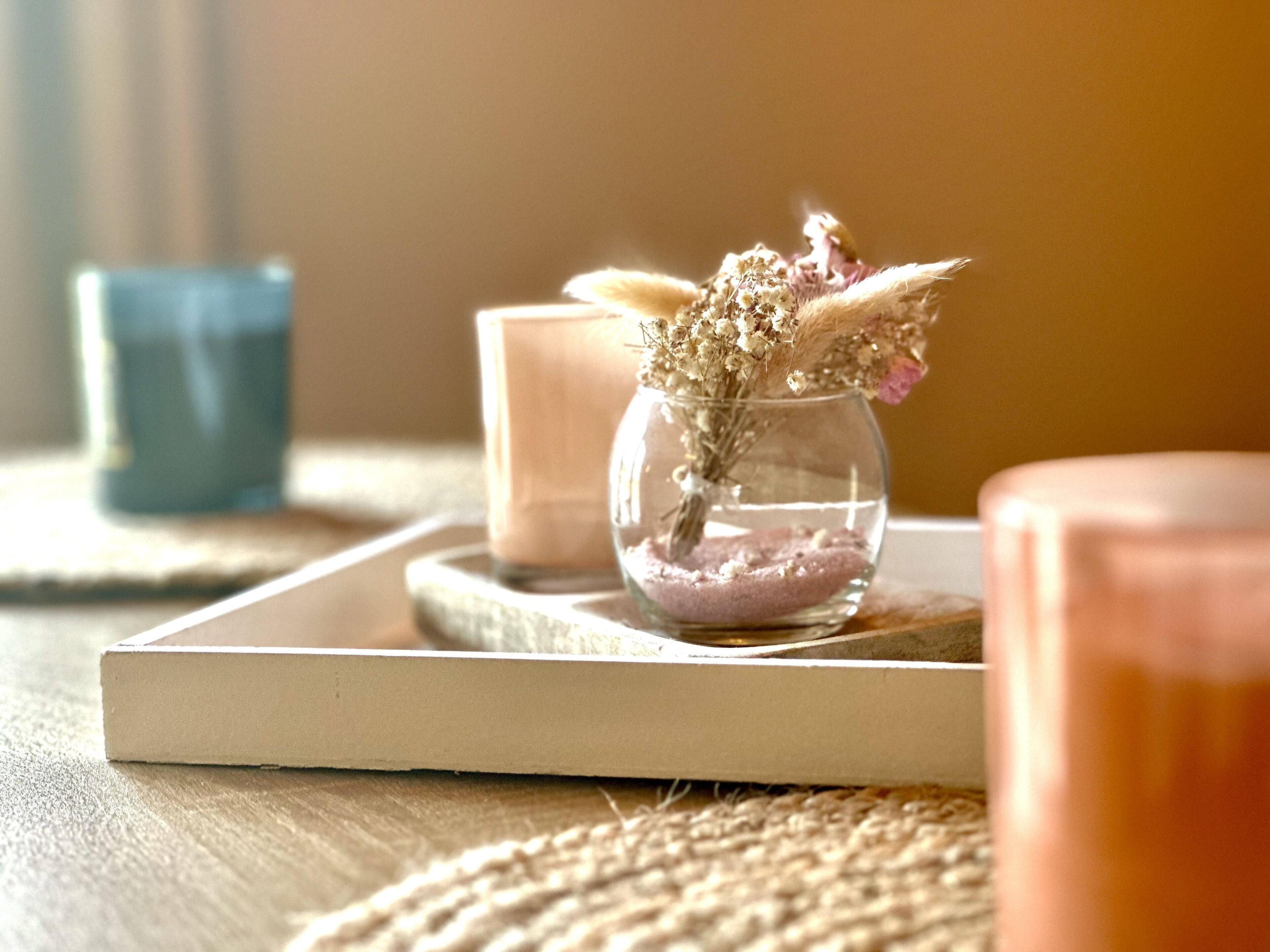 A candle holder with dried flowers on a wooden surface.